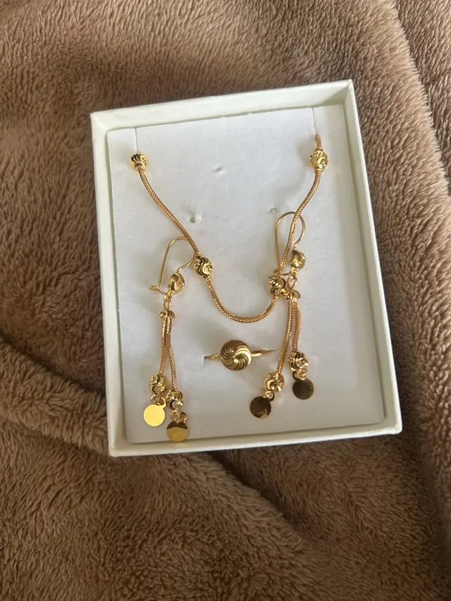 A gold necklace and earring set in its presentation box